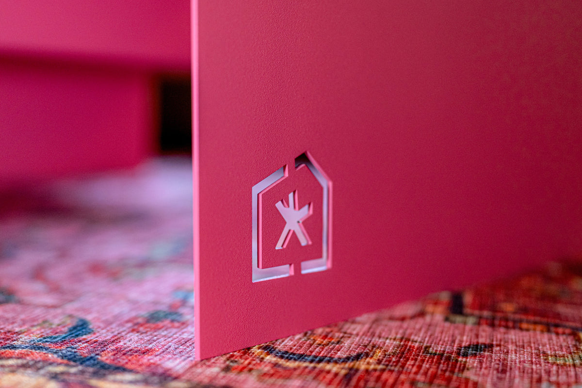 Nahaufnahme der pulverbeschichteten Oberfläche: cale-Logo als Aussparung im pinken Stahl des Couchtischs AENNA